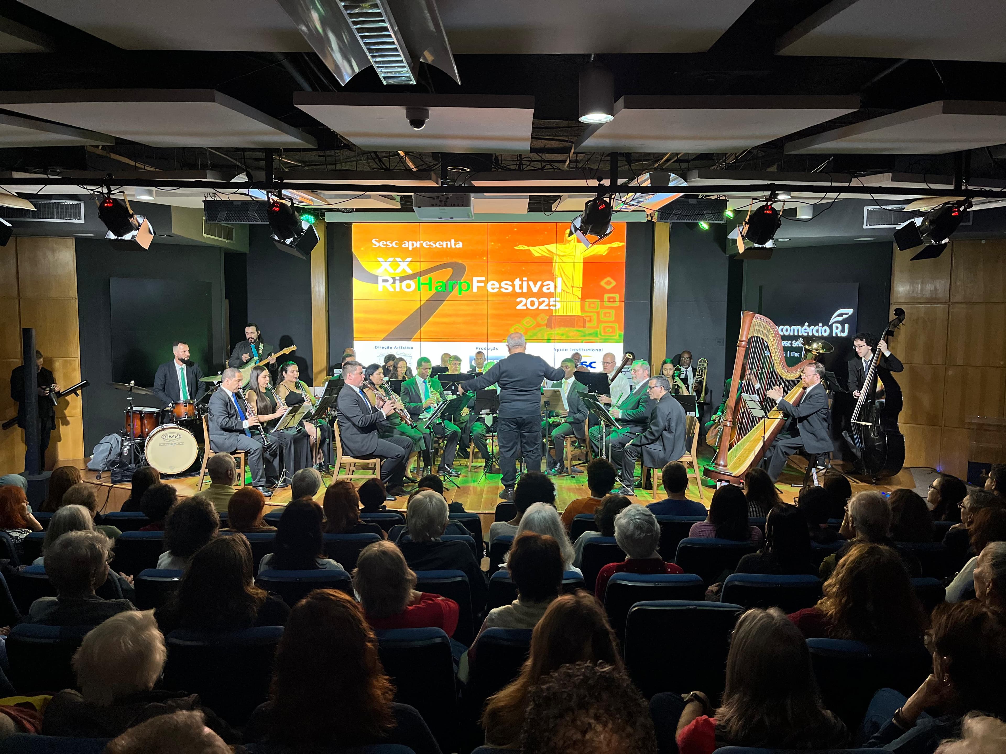 A full orchestra playing on stage in a concert hall, viewed from the audience.